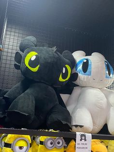 two stuffed animals sitting next to each other on a shelf in a store with yellow and blue eyes