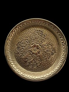 an ornate brass plate on a black background