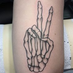 a black and white photo of a hand holding two fingers tattoo on the right thigh