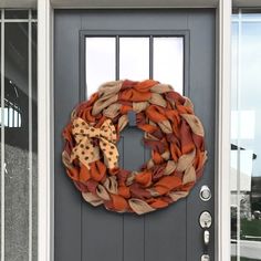 a wreath on the front door of a house that is decorated with orange and brown fabric