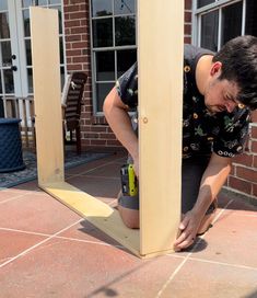 a man kneeling down next to a tall wooden pole on top of a brick floor