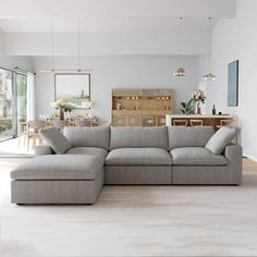 a living room with a large sectional couch and wooden table in the background, along with an open floor plan