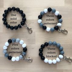 three bracelets with black, white and grey beads are shown on a wooden surface