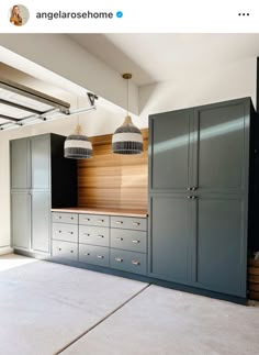 an empty room with blue cabinets and lights hanging from the ceiling in front of it