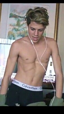 a shirtless young man wearing headphones while listening to music