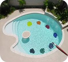 an above ground pool with colorful balls in the water and a paintbrush next to it