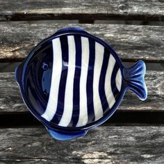 a blue and white striped fish dish sitting on top of a wooden table next to a bench