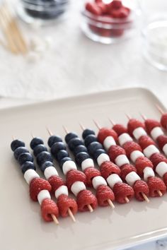 red, white and blue skewered raspberries are arranged on a plate