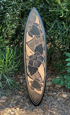 a wooden surfboard sitting on the ground in front of some bushes