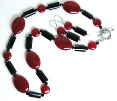 Red mountain jade, black tourmaline necklace (19 inches) with a sterling silver toggle clasp. The matching earrings are on sterling silver leverbacks with a 1.4-inch drop. Red mountain jade is a gemstone of color-enhanced high-grade dolomite marble from Asia. Both red mountain jade and tourmaline are gemstones. There are two shapes of red mountain jade beads: flattened ovals (25 x 18 mm) and flattened round beads (11 mm in diameter).The black tourmaline beads are flattened cylinders (16 x 9 mm).There are also 4 mm black faceted beads in the necklace. Red mountain jade is the gemstone of October-November. Tourmaline is a birthstone of October. Elegant Onyx Dangle Jewelry, Elegant Single Strand Onyx Jewelry, Elegant Jade Round Beads Jewelry, Elegant Jade Jewelry With Round Beads, Gift Onyx Single Strand Jewelry, Single Strand Onyx Jewelry Gift, Elegant Jade Beaded Jewelry, Elegant Adjustable Onyx Necklace, Sterling Silver Round Beads Fine Jewelry