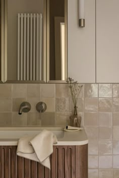 a bathroom sink sitting under a mirror next to a radiator and towel rack