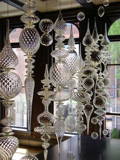 many glass balls hanging from the ceiling in front of a window with windowsills