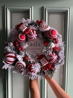 someone holding up a wreath with candy on it