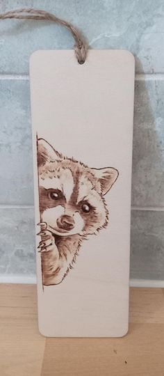 a wooden sign with a drawing of a raccoon