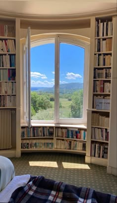 a bedroom with a large window and bookshelves filled with books on the shelves