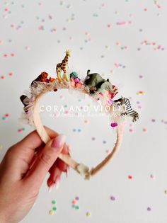 a hand holding a small headband with tiny figurines on top of it