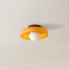 an orange and white light fixture hanging from the ceiling in a room with gray walls