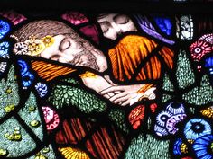 a close up of a stained glass window with a man and woman hugging each other