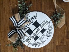 a personalized wooden sign on a wood floor with greenery and ribbon tied around it