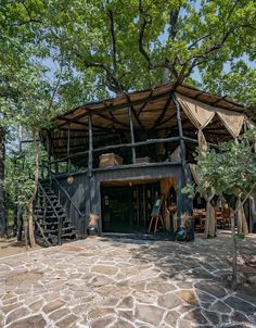 a wooden structure sitting in the middle of a tree filled forest with stairs leading up to it