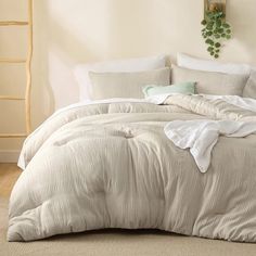 a bed with white sheets and pillows in a room next to a ladder on the wall