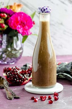 a glass bottle filled with brown liquid next to flowers and spoons on a table