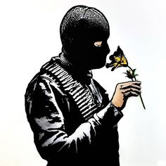 a person in a black mask holding a flower with the words know more about anarchy click here