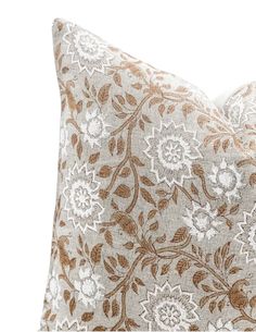 a white and gold floral pillow on a white background with an orange flowered design