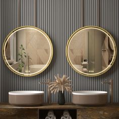 two round mirrors hanging on the side of a wall next to sinks in a bathroom