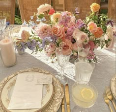 the table is set with plates, silverware and flowers