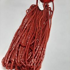 a string of red glass beads with a white tag hanging from it's end