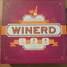 the front cover of a winerd game on a wooden table with an orange ribbon around it