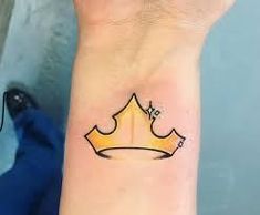 a small yellow crown tattoo on the wrist