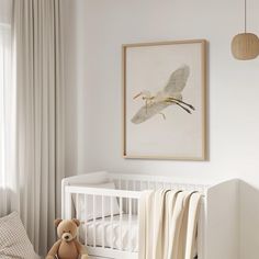 a white crib with a teddy bear in it and a painting on the wall