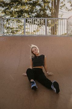 a woman sitting on top of a skateboard ramp