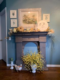 a blue room with a fireplace and pictures on the wall, vases filled with flowers