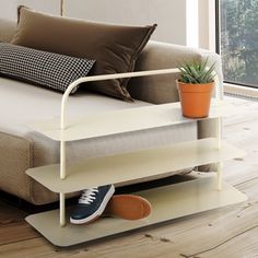 a bed with a white metal frame and brown pillows on it next to a potted plant