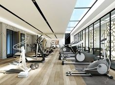 there are many exercise machines in this gym room with wood flooring and glass walls