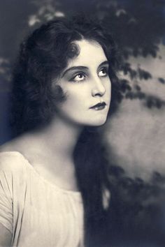 an old black and white photo of a woman with her eyes wide open looking into the distance