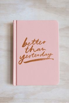 a pink notebook with the words better than yesterday written in gold foil on top of it