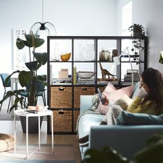 a woman sitting on top of a couch next to a plant in a living room