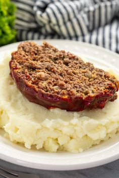 a white plate topped with mashed potatoes and meatloaf