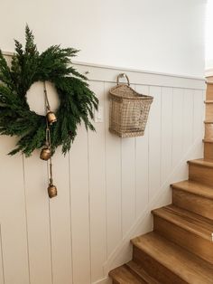 a christmas wreath hanging on the wall next to some stairs with bells and ornaments around it