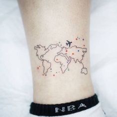 a small world map tattoo on the right side of the ankle, with an airplane flying over it