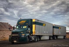 a large semi truck driving down a dirt road