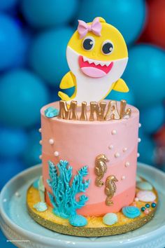 a pink and yellow cake with a baby shark on top