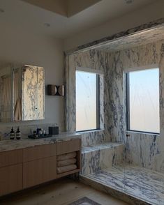 a bathroom with marble walls and two windows