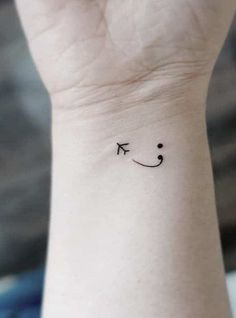 a smiley face tattoo on the wrist with an arrow in it's middle finger