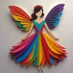 a paper cut out of a woman wearing a rainbow colored dress with wings and a tiara on her head