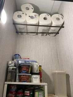 there are several rolls of toilet paper on the shelf above the refrigerator door in this small room